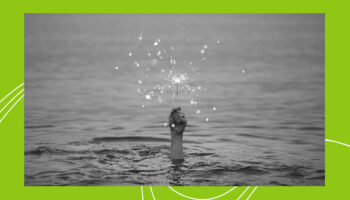 A hand coming out of the water holding a lit sparkler